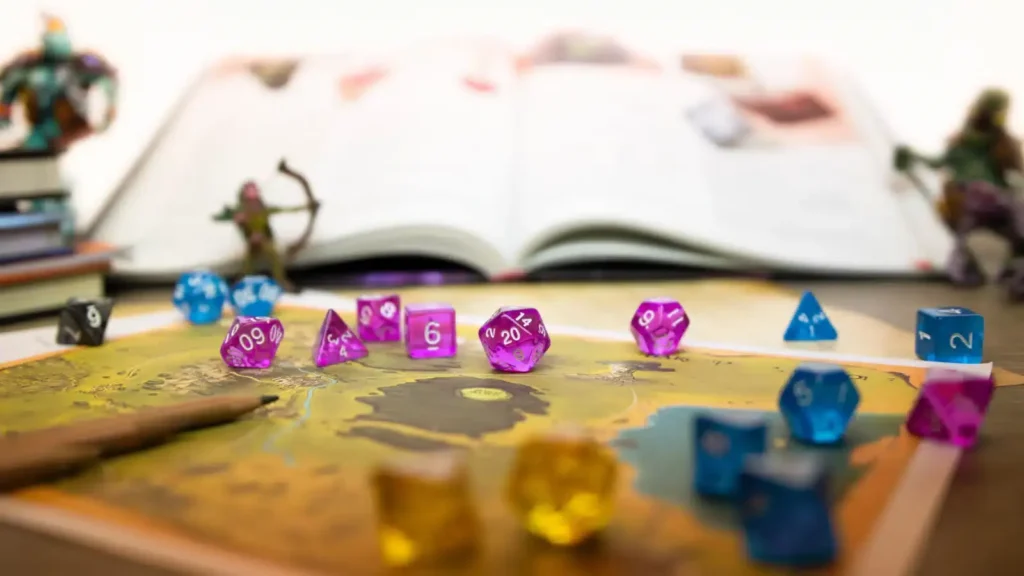 Set di dadi poliedrici colorati (viola e blu) sparsi su una mappa di gioco, con un manuale aperto e miniature sullo sfondo, rappresentando una sessione di giochi di ruolo.