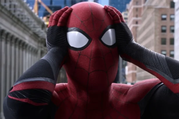 Spider-Man tiene le mani sulla testa in una scena iconica, circondato da grattacieli in una città.
